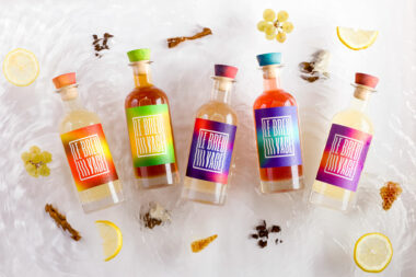 Photographie culinaire des 5 bouteilles de cocktail qui flottent dans l'eau au milieu des ingrédients.