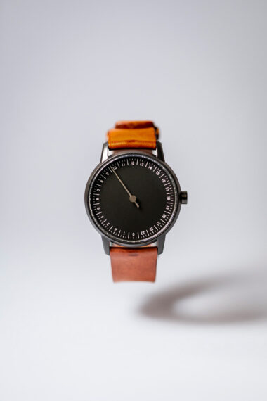 Photographie minimaliste d'une montre "the Slow Watches" qui flotte dans les airs