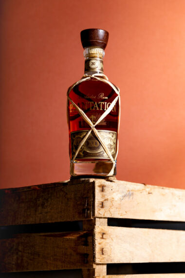 Photographie de spiritueux hero shot d'une bouteille de Rhum Planteray sur sa caisse de transport en bois.